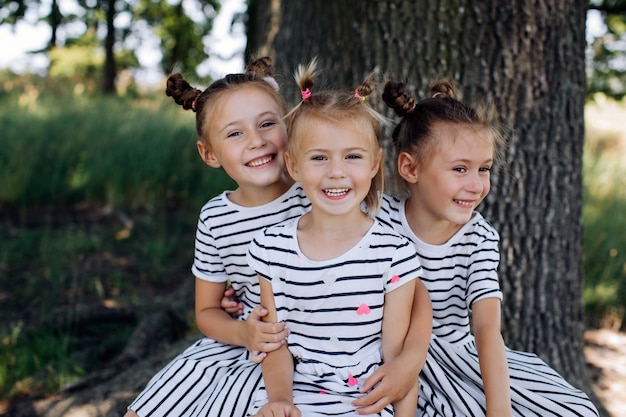 写真 ドレスを着た3人の幸せな姉妹が公園で笑顔と抱擁