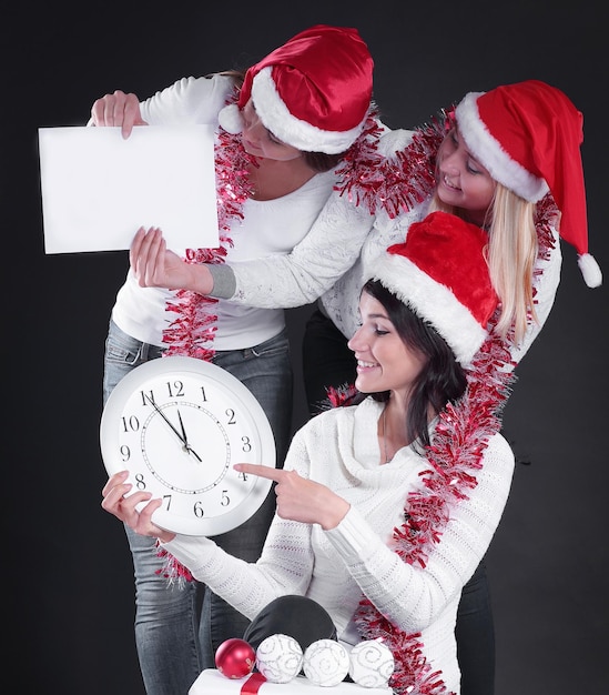 시계와 크리스와 산타 클로스의 의상을 입은 세 명의 행복한 여성