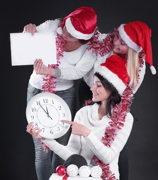 Three happy women in costume of Santa Claus with clockand Chris