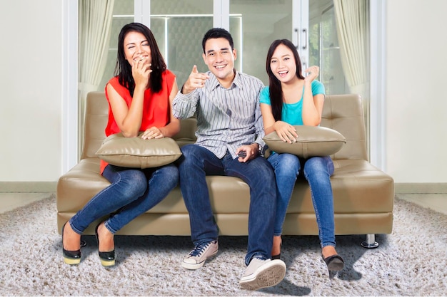 Three happy young people watching TV at home