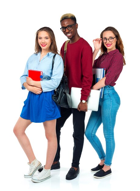 Photo three happy young teenager students standing and smiling with books laptop and bags isolated on white background