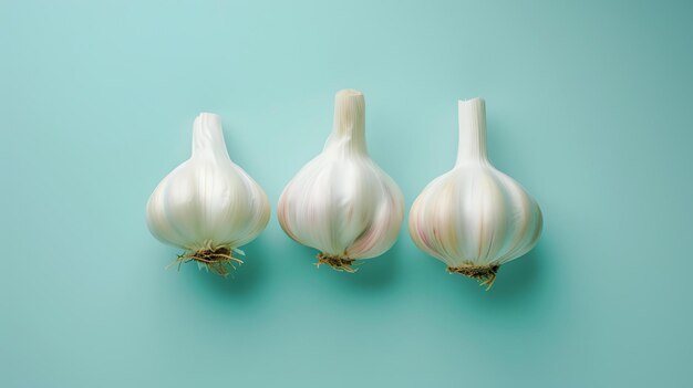 Foto tre teste di aglio su uno sfondo blu l'aglio è bianco e ha una leggera sfumatura rosa i chiodi di garofano sono visibili in alcune delle teste