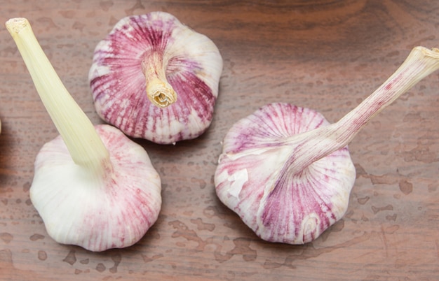 Three heads of garlic on a wooden table, kid from above, close-up