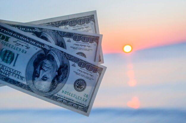 Three hundred dollar bills on background of sea surface at sunset dawn