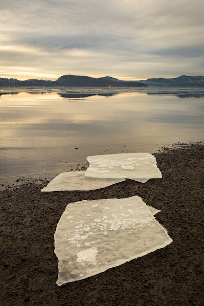 Foto tre banchi di ghiaccio sulla sabbia scura sulla spiaggia norvegese. mare calmo, nebbia e nebbia. hamresanden, kristiansand, norvegia