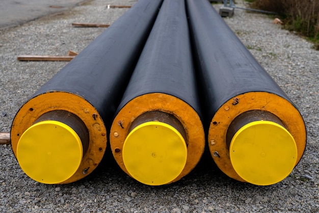 Three isolated heating pipes with yellow plastic plugs lie on a construction site