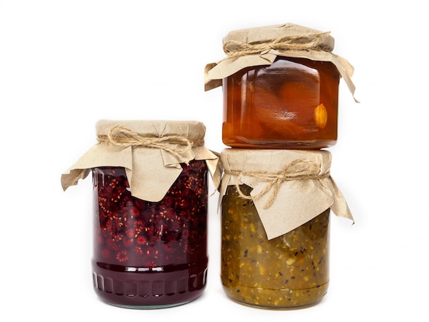 Three jars of different jam on a white surface