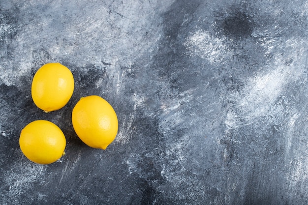 Three juicy ripe lemons placed marble surface