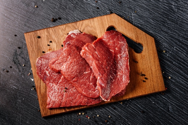 Three juicy slices of beef for steaks on a cutting board.