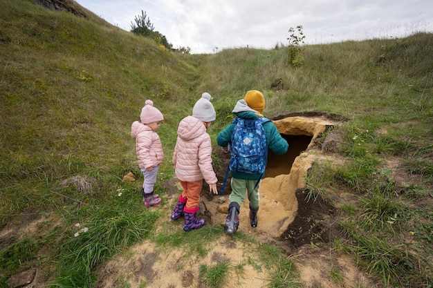 3 人の子供が山の石灰岩の石の洞窟を探索します。