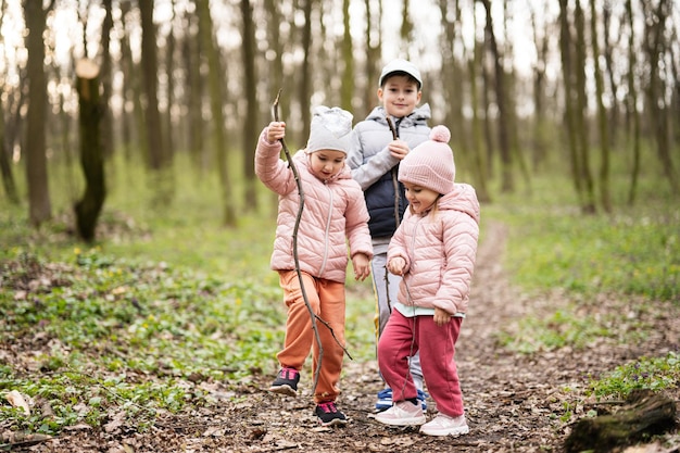 3 人の子供がハイキングと春の森を発見幸せな子供時代