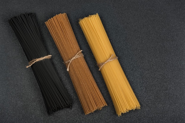 Three kinds of pasta on black surface