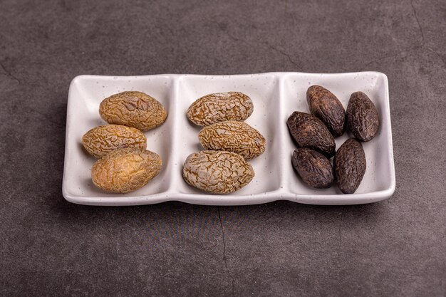 Three kinds of pickled olives are placed in three squares of a long white pot on a gray background