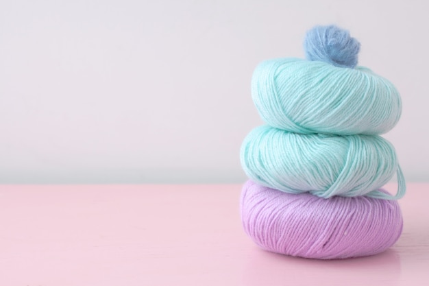 Three large balls of lilac and turquoise color are stacked on top of each other a small blue ball on a pale pink table of pastel colors.