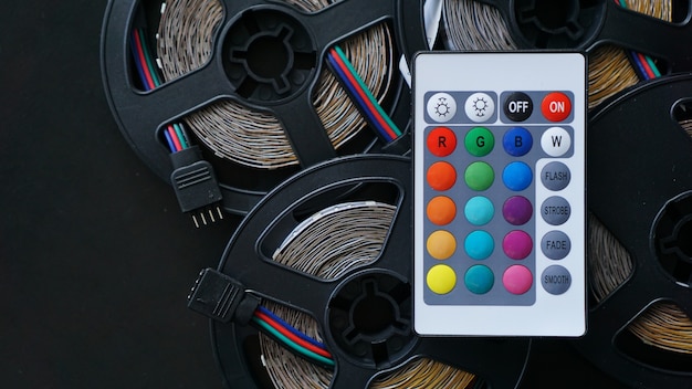 Three Led strip coils closeup. Diode with control panel for switching colors on dark background.