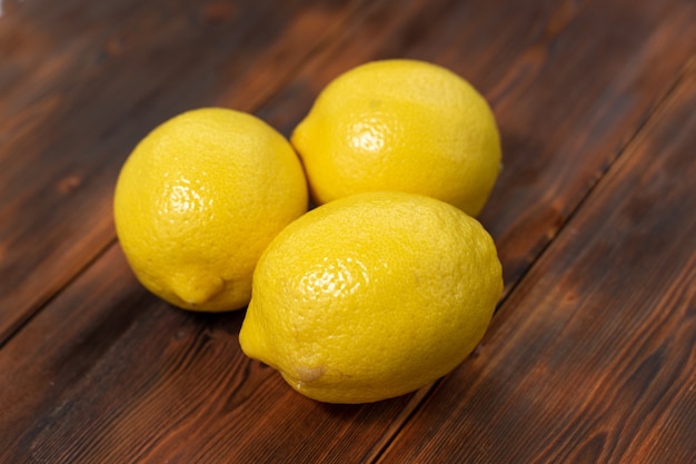 Three lemons on a wooden background