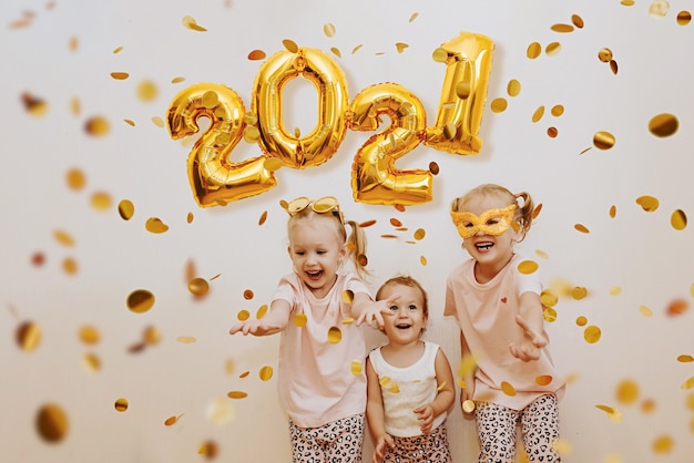 Three little girls are enjoying the flying golden confetti