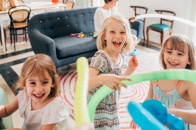 Three little sisters indoor at home playing with balloon having fun smiling