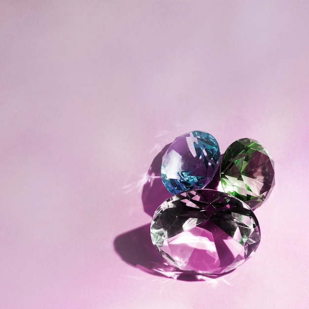 Three luxurious shiny diamonds on pink background