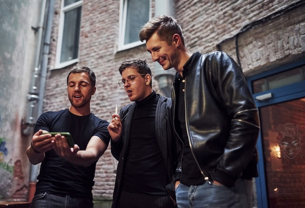 Three male friends stands outside the bar