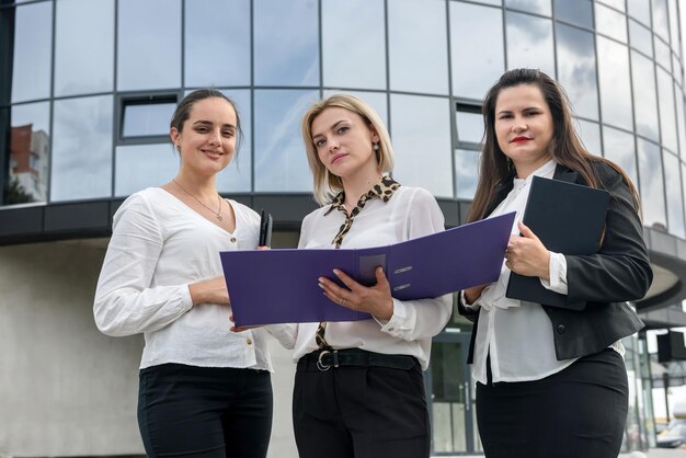 Three managers with folders posing outside office building