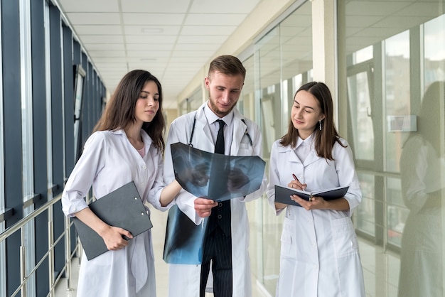 Stagista medico tre guardando attraverso l'immagine a raggi x dei polmoni per polmonite virale del paziente covid-19 in clinica. concetto medico