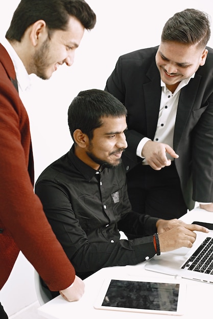  Three men discussing ideas. White wall. Indian nationality.