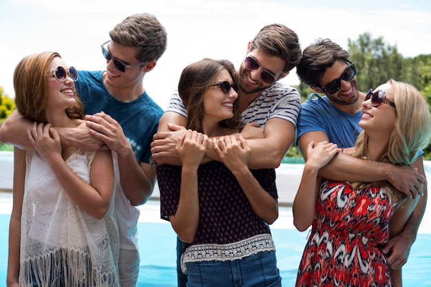 Photo three men embracing women near pool