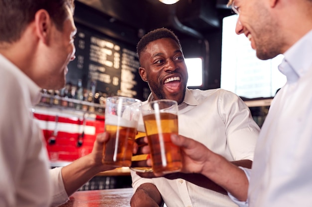 Three Men Making A Toast As They Meet For Drinks And Socialize In Bar After Work