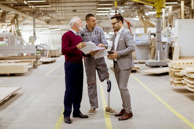 Photo three men standing and discuss in furniture factory