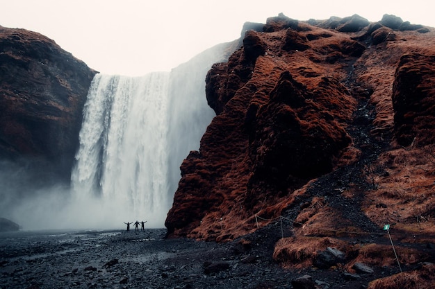 Three Men Standing Near Waterfalls