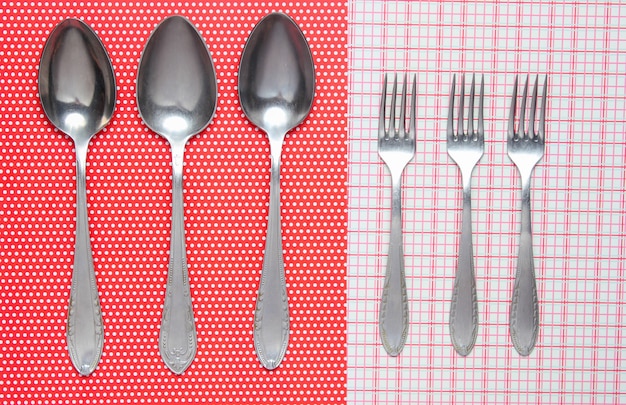 Three metal spoons and forks on tablecloth