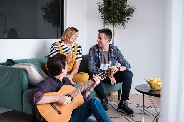 Three middleaged friends having a few beers relaxing and playing the guitar Concept Lifestyle disconnection enjoy