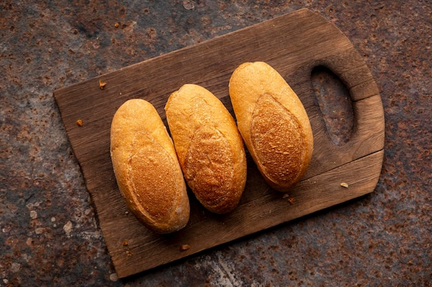 Foto tre mini baguette francesi in tagliere di legno sul vecchio fondo di struttura del metallo ruggine marrone rossastro vista dall'alto concetto di design a tema cibo vintage piatto