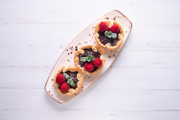 Three mini tarts with raspberries on a white platter