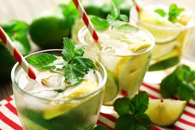 Three mojito drinks with lime lemon and mint on red stripe napkin