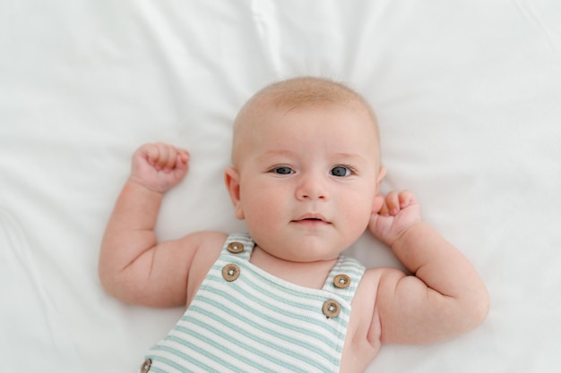 Photo three months baby boy on white background smiling happy newborn on green blanket small fingers