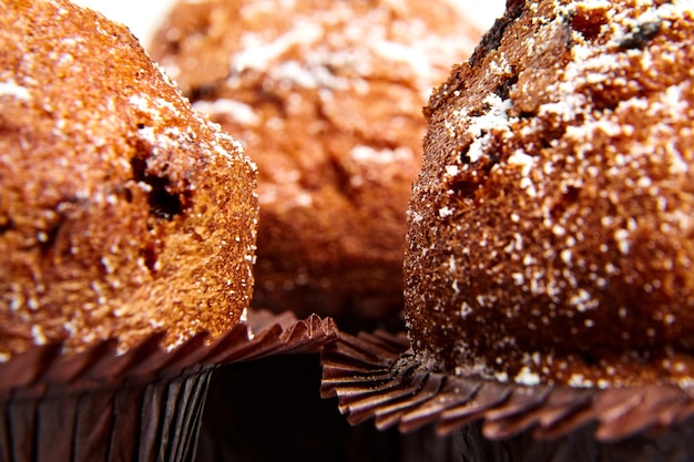 Three muffins with chips of chocolate and powdered sugar