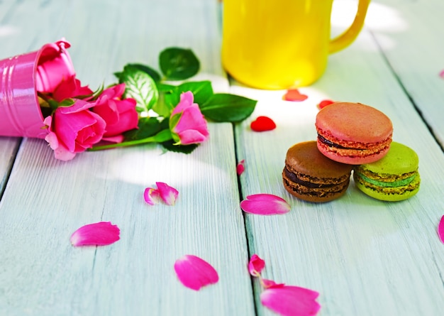 Three multi-colored almond macaroons and a yellow mug 