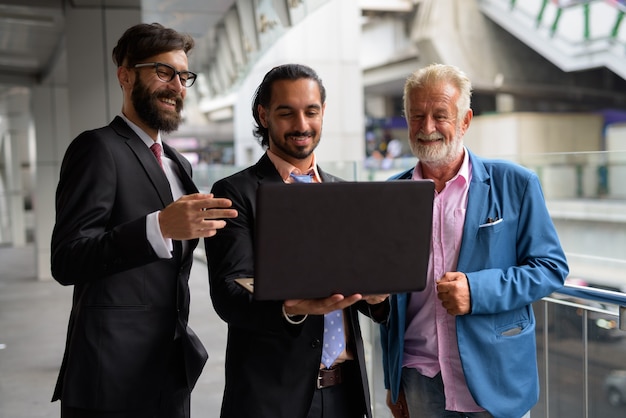 Three multi ethnic bearded businessmen together around the city