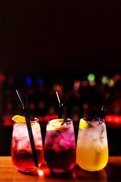 Three multicolored alcoholic cocktails decorated with lime and oranges on the bar counter Mixing an alcoholic cocktail in a nightclub pub restaurant