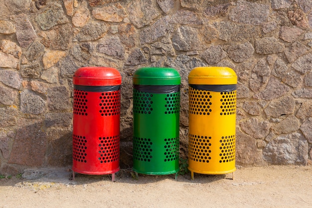 Three multicolored recycle bins for waste near the wall. Sort waste