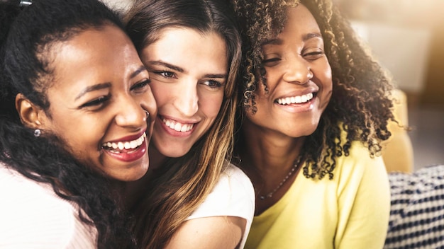 Three multicultural young women hugging together beautiful\
females portrait friendship concept