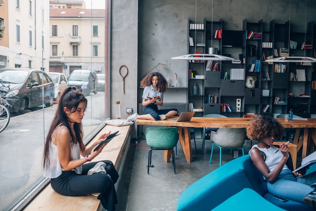 Tre giovani donne di affari multirazziali che lavorano nell'ufficio di coworking moderno