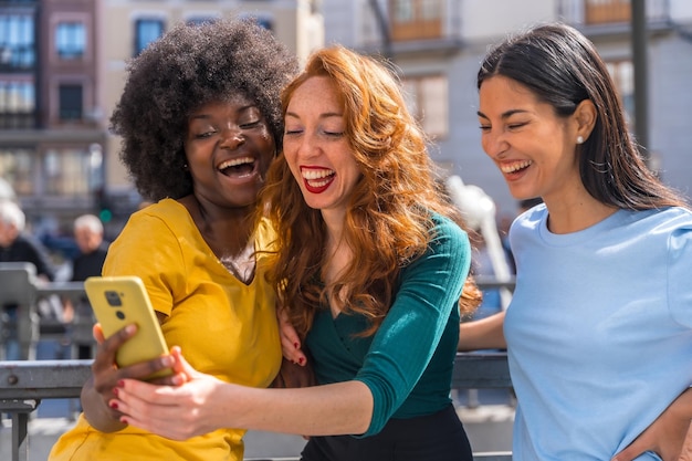 Foto tre giovani donne multirazziali per strada prendendo un selfie in città all'aperto amicizia concetto femminista e tecnologico