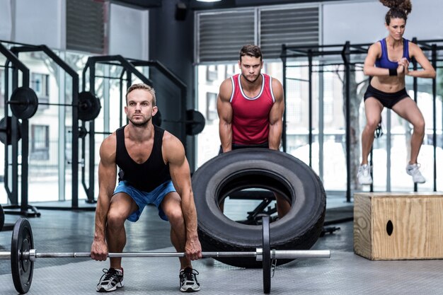 Three muscular athletes lifting and jumping 