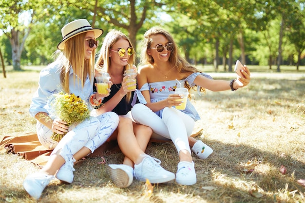 Photo three nice girls having fun in the park and make selfie excellent sunny weather beautiful figures