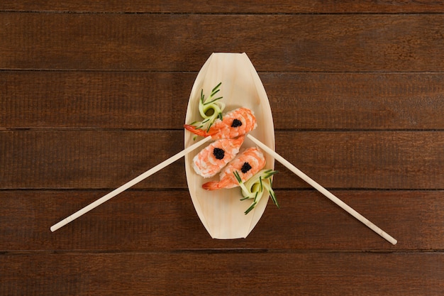 Foto i tre sushi di nigiri sono servito con le bacchette in zolla di legno della barca