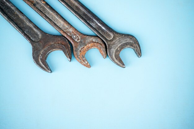 Три старых ржавых гаечных ключей на синем фоне. Оборудование для мастерских.