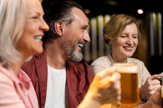 写真 ビールを飲みながらレストランで笑っている3人の年上の友人